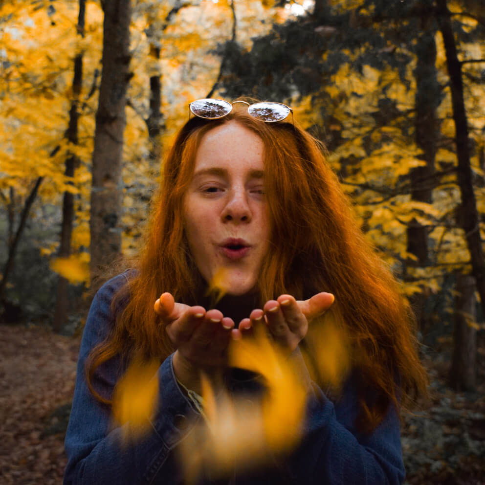 A girl blowing autumn leaves